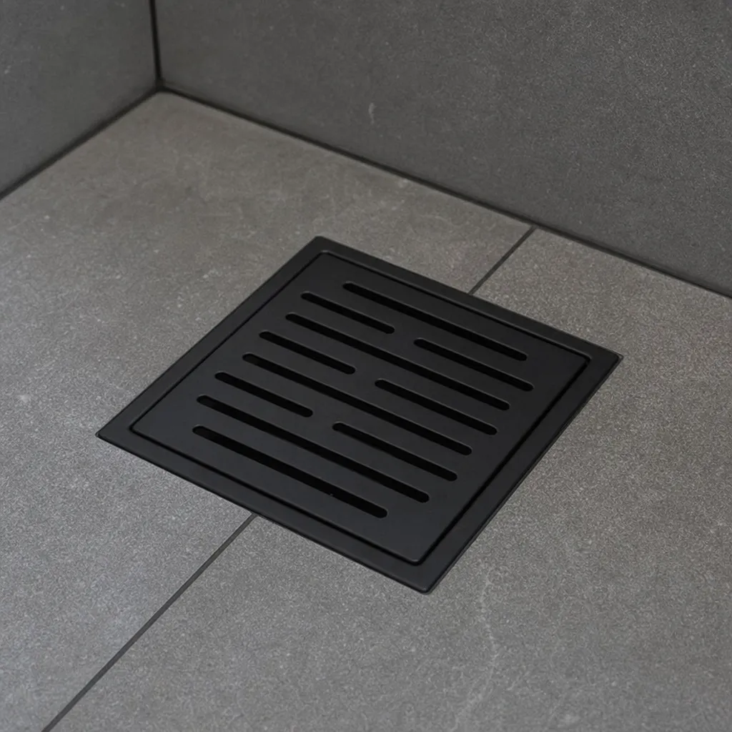 A Close Up Of A Sleek, Matte Black Decorative Drain Cover In A Tiled Shower